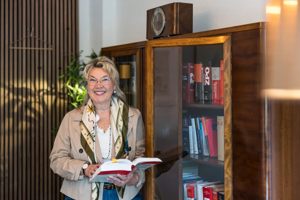 Kirsten Höner-March mit einem aufgeschlagenen Gesetzbuch vor dem Bücherschrank