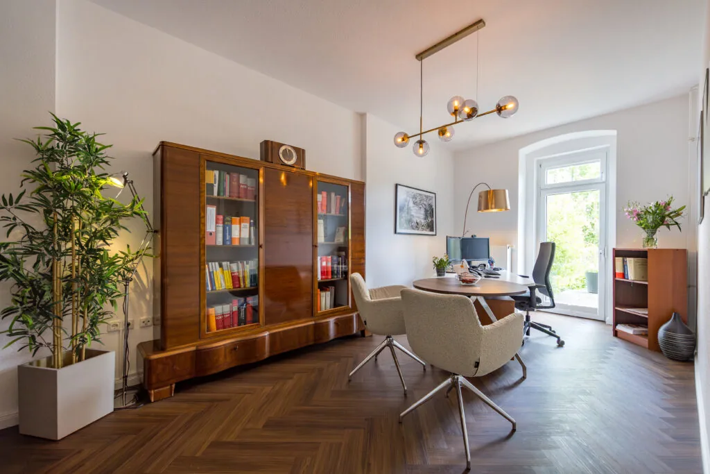 Büro der Kanzlei mit Bücherschrank, Schreibtisch und hellem Besprechungsplatz